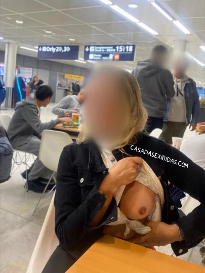 Esposa exibicionista mostrando o peito no aeroporto.